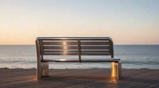 Banc public en acier inoxydable installé sur une promenade côtière, symbole de durabilité face aux embruns marins
